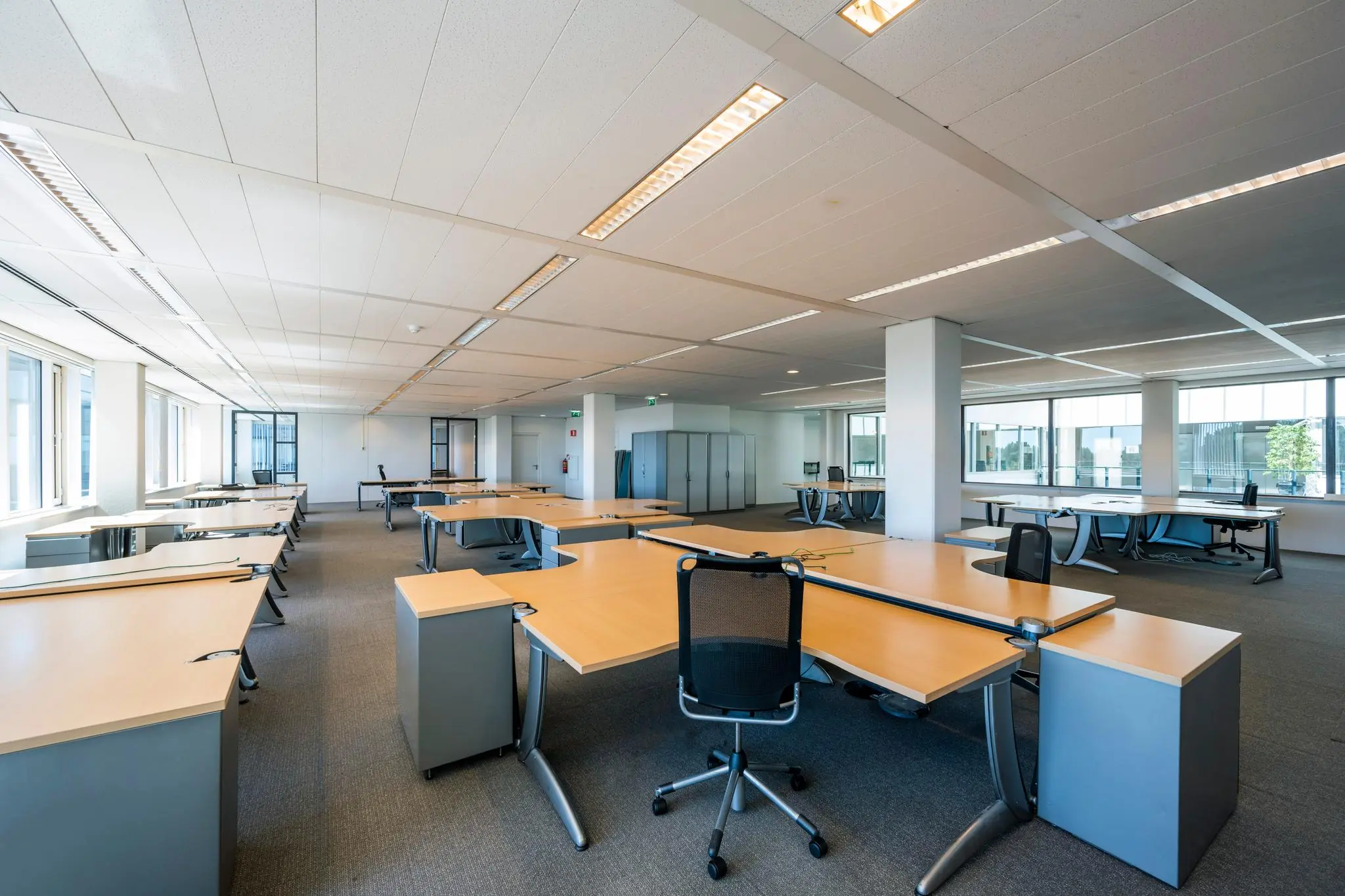 Ruime, moderne kantooretage aan de Thomas R. Malthusstraat met meerdere bureaus en grote ramen.